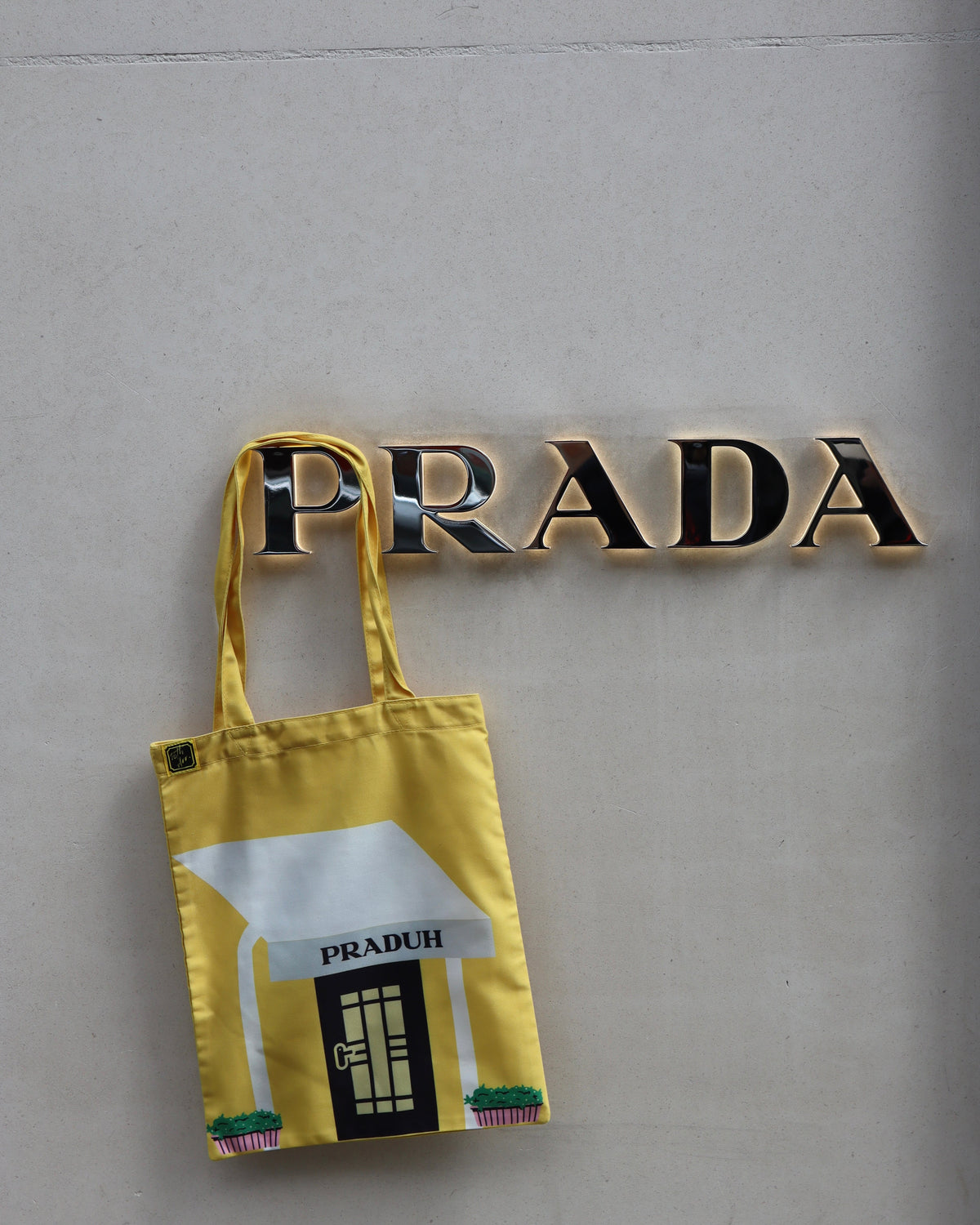 Capri tote hung on a gallery wall beneath gold lettering