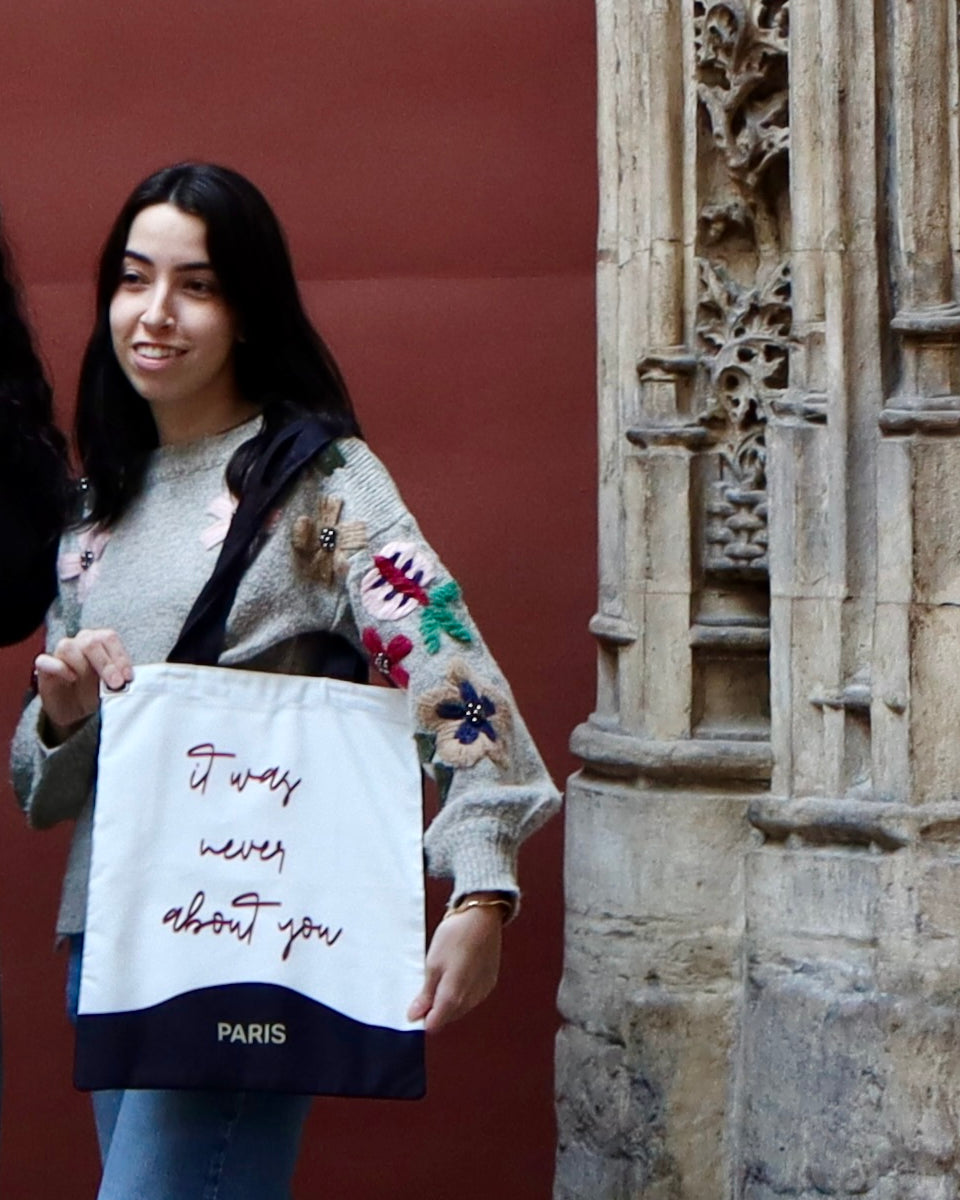 Never About You tote held by a carved stone doorway